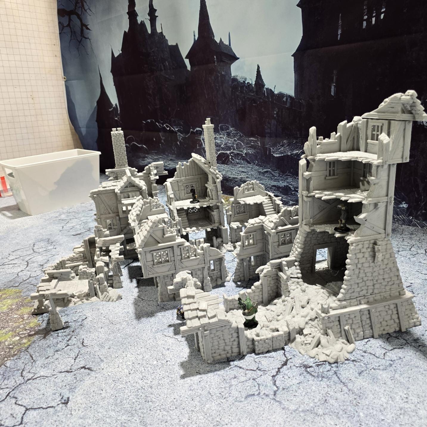 three intricately detailed ruined buildings and a towering structure, showcasing crumbling stone walls, exposed beams, and a hauntingly desolate atmosphere, perfect for bringing medieval and fantasy battles to life on your tabletop.