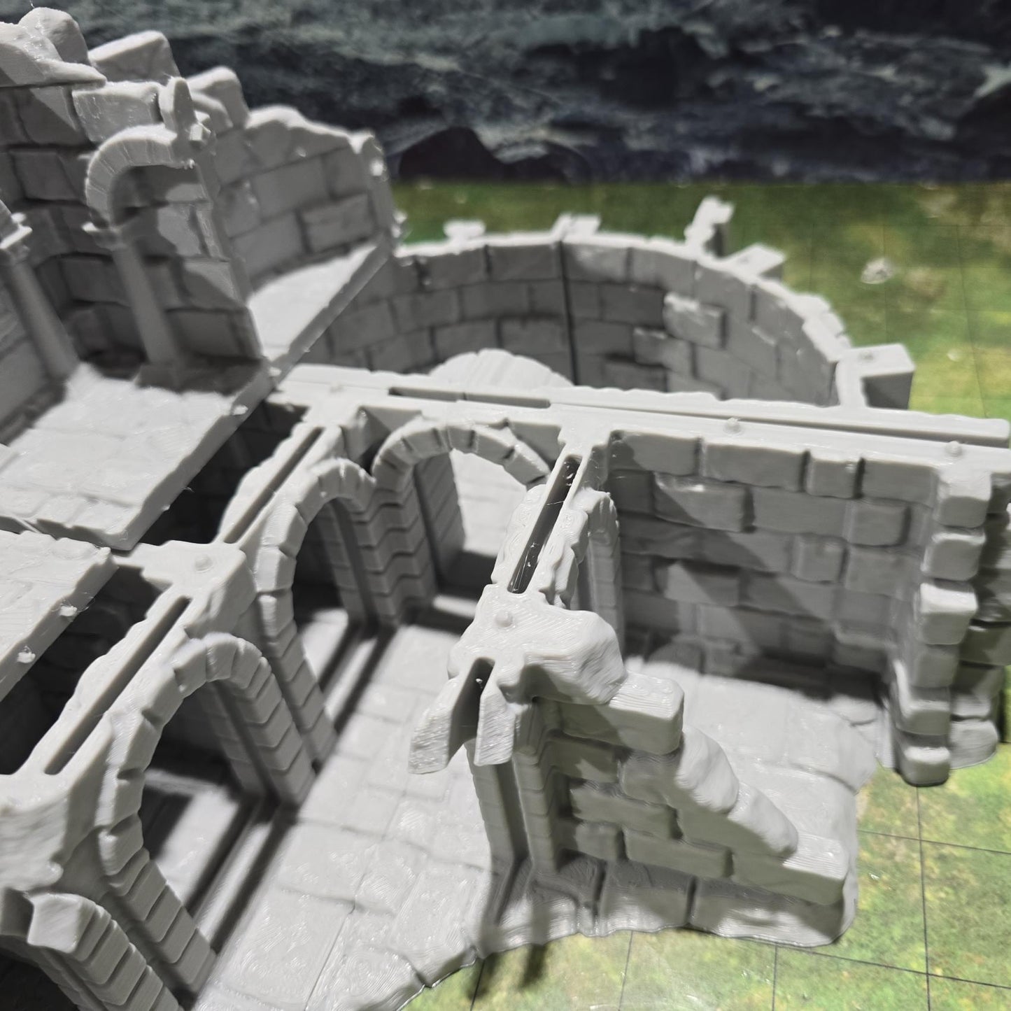 Explore the Arkenfel Barracks Building Ruin, featuring a medieval fortress design with detailed crumbling walls and strategic interior spaces, perfect for historical or fantasy tabletop games.