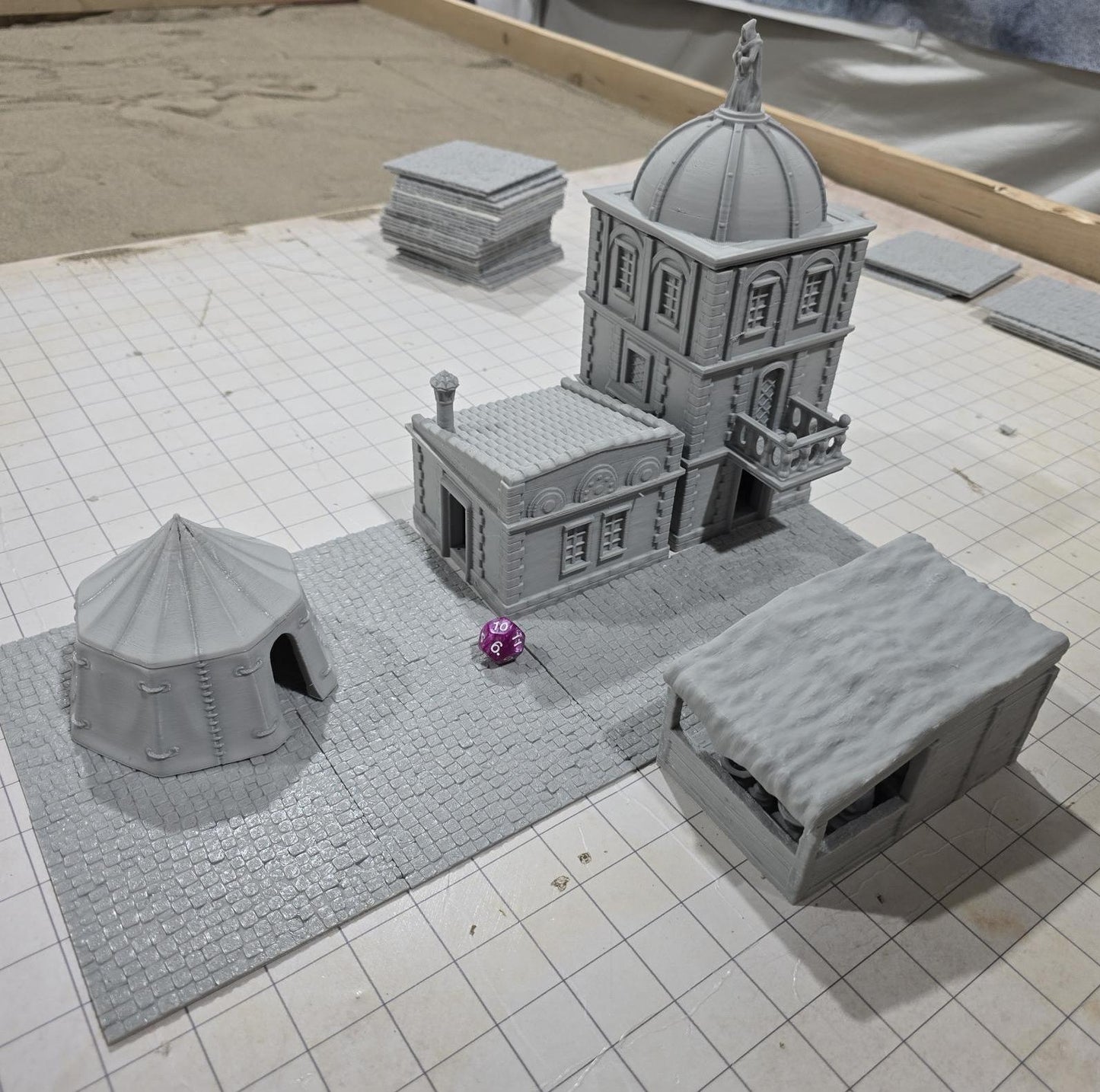 Complete medieval street set with two detailed buildings, a market tent and stall, and five cobblestone roads, perfect for tabletop role-playing games.
