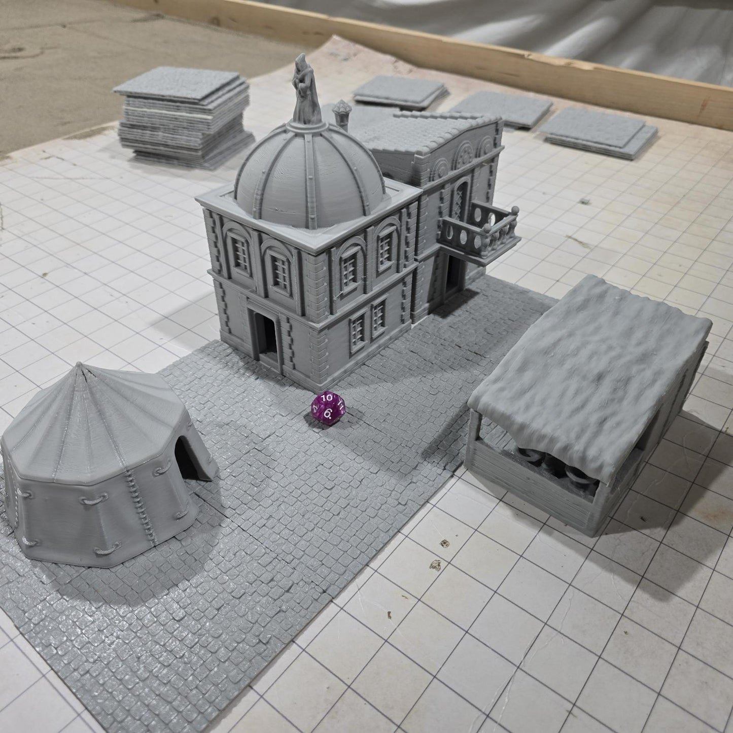 Complete medieval street set with two detailed buildings, a market tent and stall, and five cobblestone roads, perfect for tabletop role-playing games.