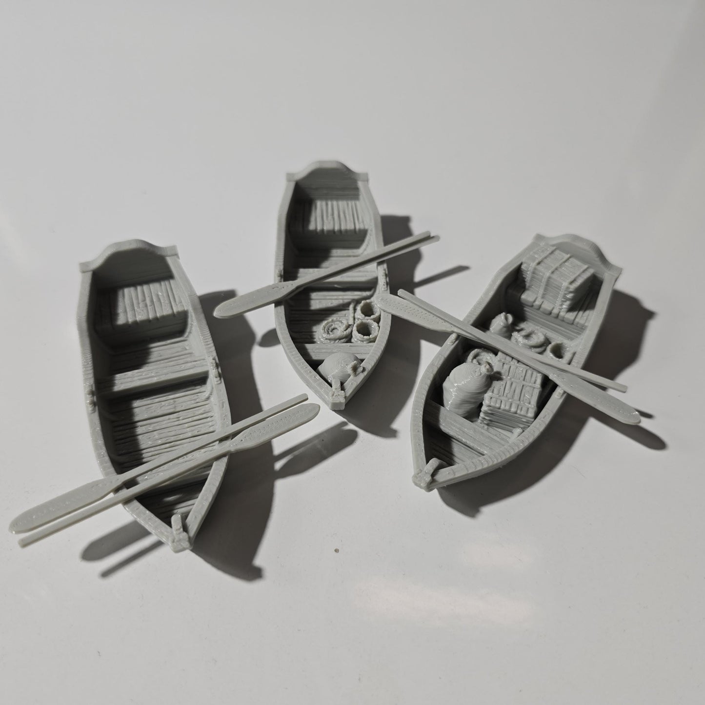Set of 3 medieval rowboats with crates, barrels, sacks, ropes, and oars. Available in 15mm, 28mm, and 32mm scalesβperfect for docks, rivers, and coastal scenes in fantasy and historical tabletop games.