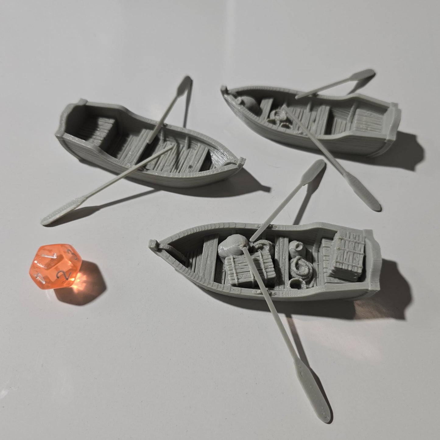 Set of 3 medieval rowboats with crates, barrels, sacks, ropes, and oars. Available in 15mm, 28mm, and 32mm scales—perfect for docks, rivers, and coastal scenes in fantasy and historical tabletop games.