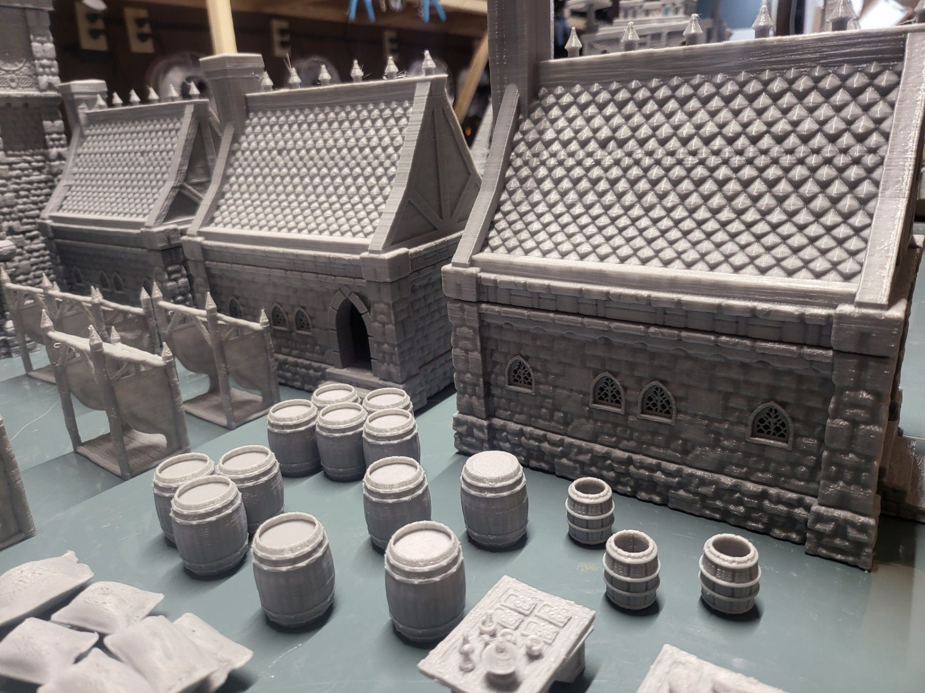 Set of 10 detailed 28mm buildings for tabletop RPGs, featuring wooden and stone structures with varied roof styles. Includes market wares and scatter terrain like barrels and crates. Perfect for village scenes in D&D, Pathfinder, and Warhammer.
