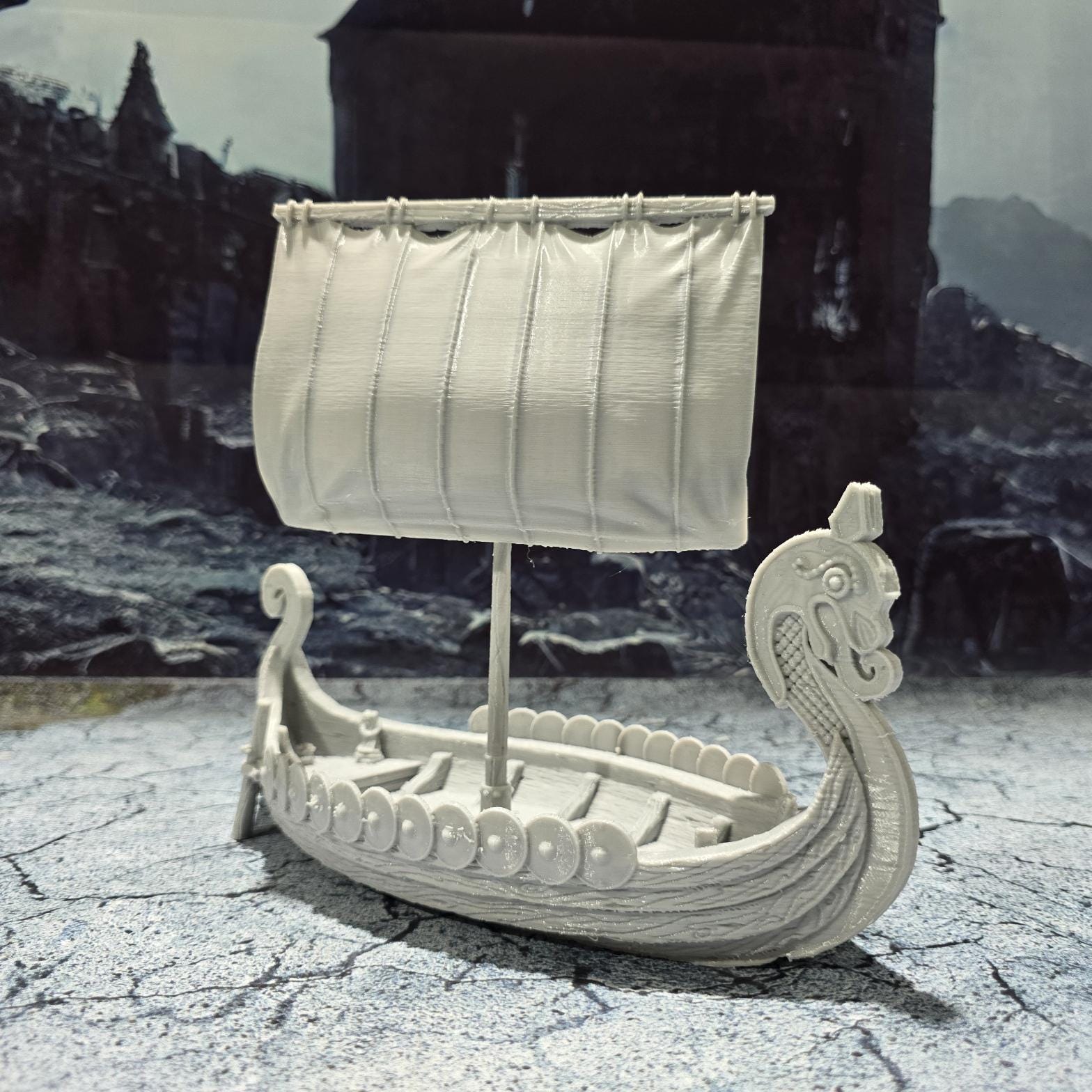The Viking Invader Ship model features a detailed dragon-head prow, shield-lined sides, and a furled sail, capturing the essence of Norse seafaring prowess, perfect for bringing epic Viking adventures to life on your tabletop.
