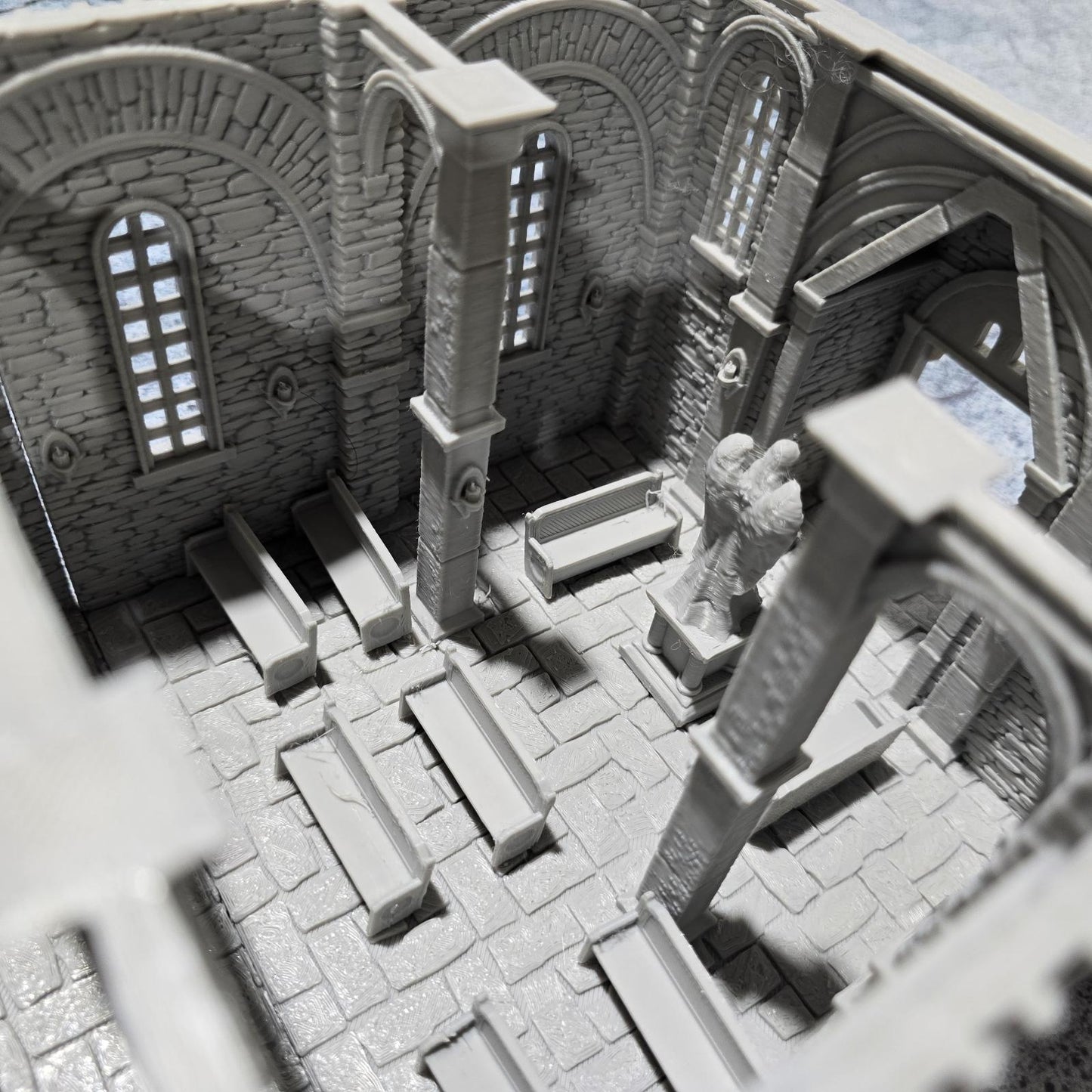 The Greendale Church of the Dale features a medieval gothic design with two angel statues and sets of pews, ideal for historical tabletop settings.