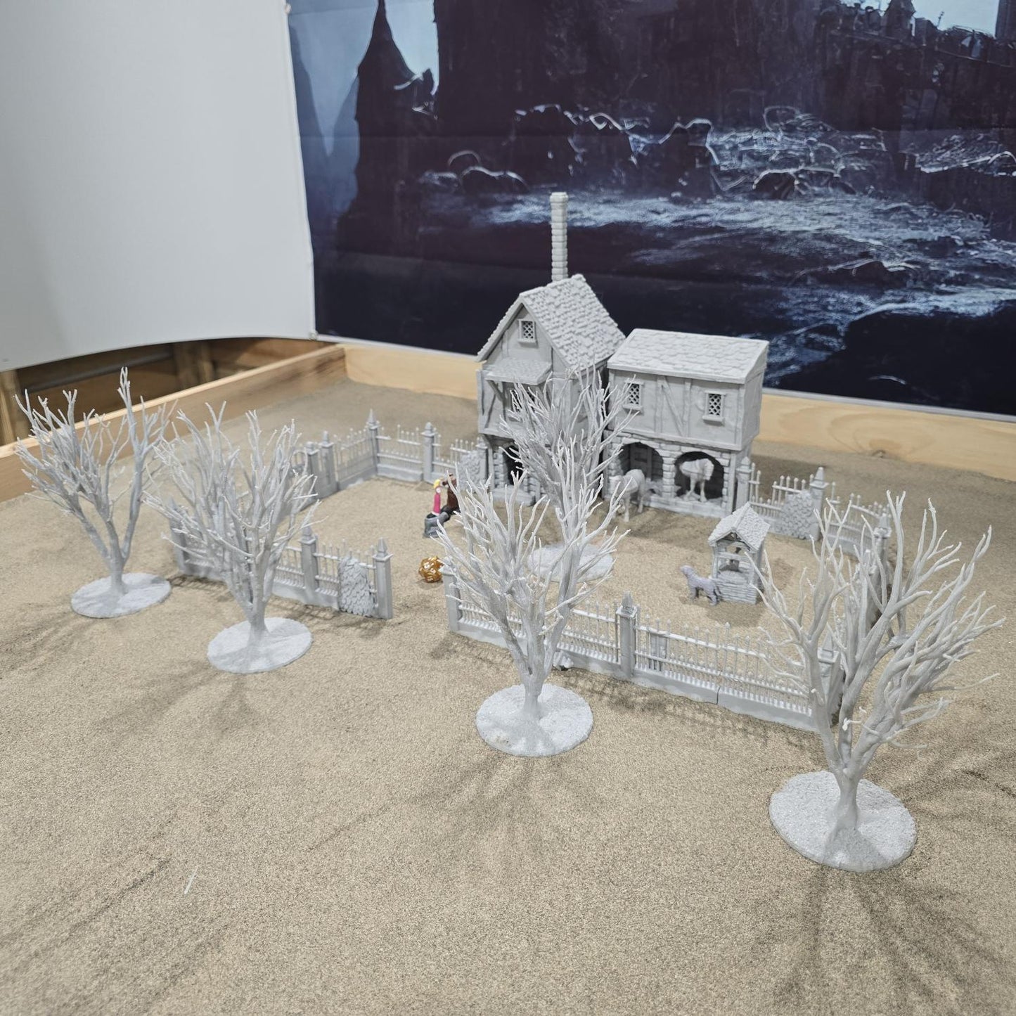 Exquisite 3D printed homestead model with detailed house, fencing, and barren trees, set against a rugged backdrop, perfect for tabletop games and dioramas.