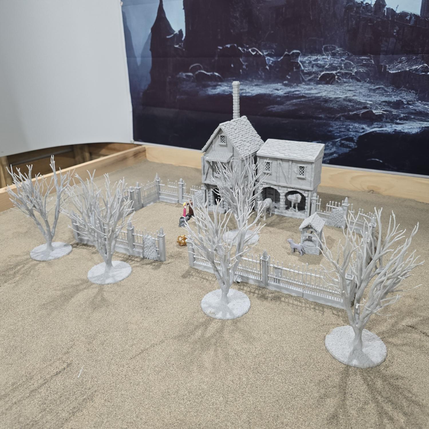 Exquisite 3D printed homestead model with detailed house, fencing, and barren trees, set against a rugged backdrop, perfect for tabletop games and dioramas.