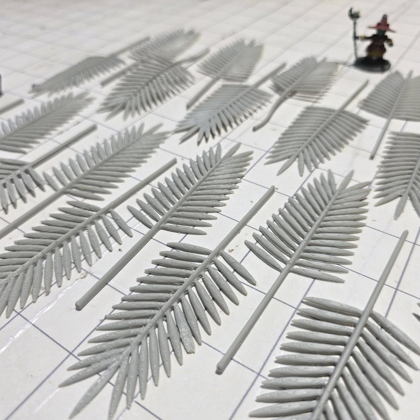 Laid across a 1&quot; grid, these 28mm-scale palm fronds form a tropical spread waiting to be shaped and painted. With identical sprigs that bend under heat, they’re perfect for scratch-building palm trees, decorating temple ruins, or fleshing out dense jungle scenes. A miniature wizard and dice provide a sense of scale, highlighting their table-ready size.