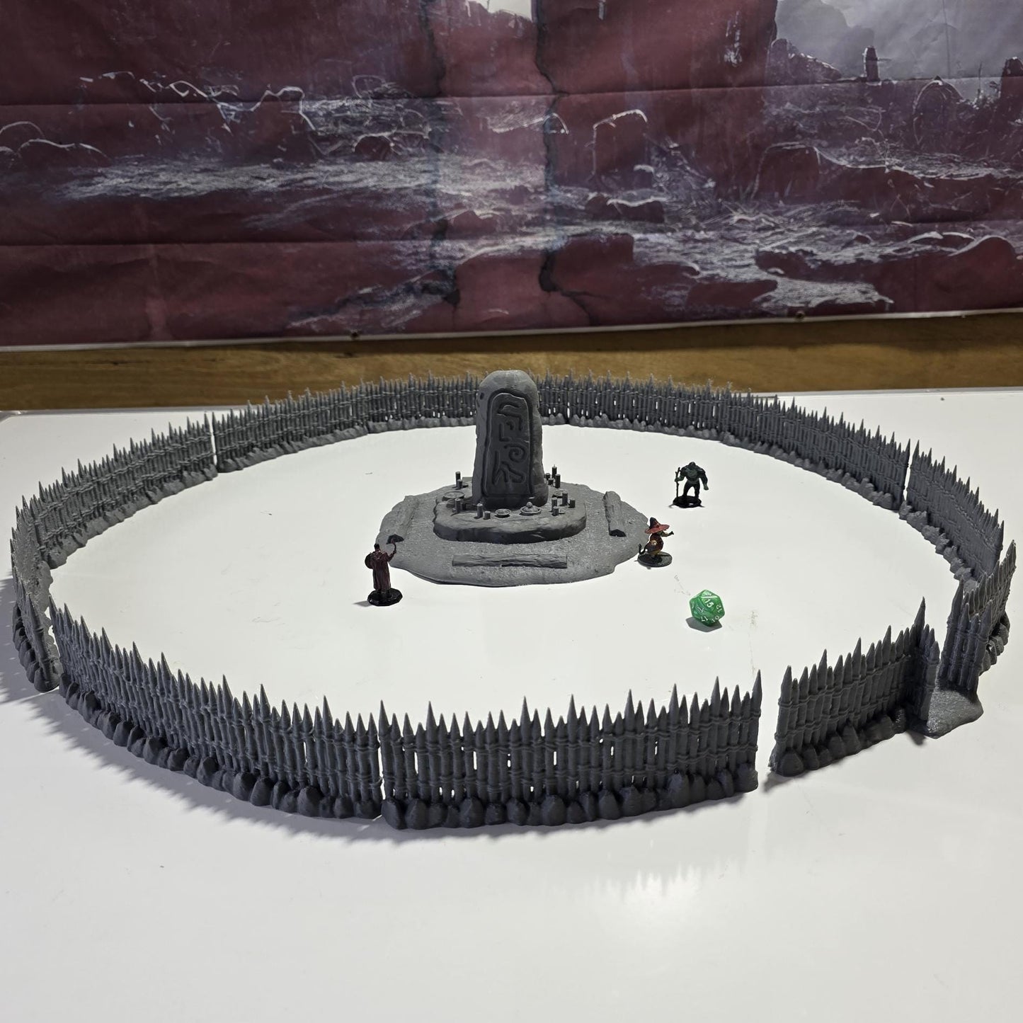 Unpainted gray PLA captures the rough ground, carved runestone, and jagged timber spikes of this 28 mm tabletop terrain set. The monolith rises from a layered base scattered with simple offerings, while the spiked walls form a full circle around the site. Each piece shows the subtle lines of 3D printed construction, ready for primer. Designed for DnD / Pathfinder / wargaming on a 1-inch grid, it stands as a stark landmark on any table.