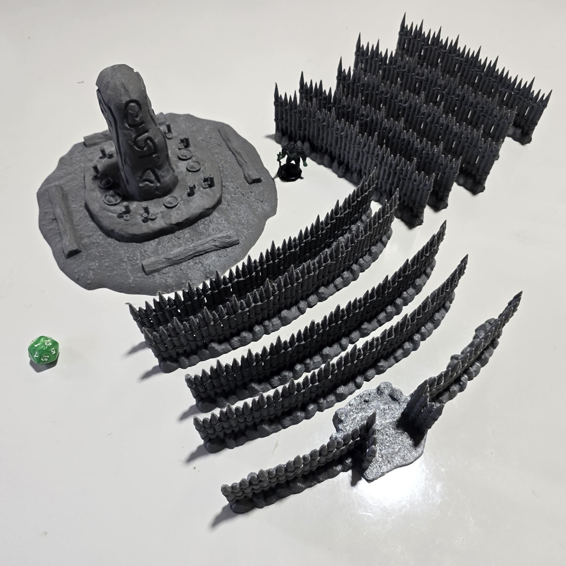 Unpainted gray PLA captures the rough ground, carved runestone, and jagged timber spikes of this 28 mm tabletop terrain set. The monolith rises from a layered base scattered with simple offerings, while the spiked walls form a full circle around the site. Each piece shows the subtle lines of 3D printed construction, ready for primer. Designed for DnD / Pathfinder / wargaming on a 1-inch grid, it stands as a stark landmark on any table.