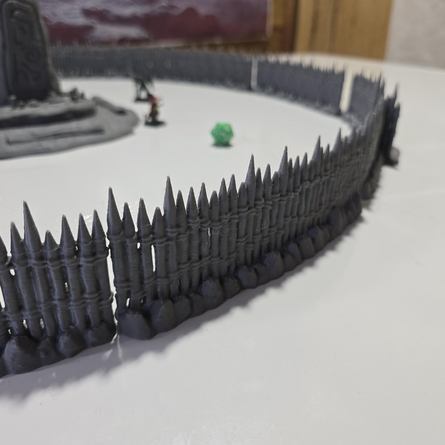 Unpainted gray PLA captures the rough ground, carved runestone, and jagged timber spikes of this 28 mm tabletop terrain set. The monolith rises from a layered base scattered with simple offerings, while the spiked walls form a full circle around the site. Each piece shows the subtle lines of 3D printed construction, ready for primer. Designed for DnD / Pathfinder / wargaming on a 1-inch grid, it stands as a stark landmark on any table.