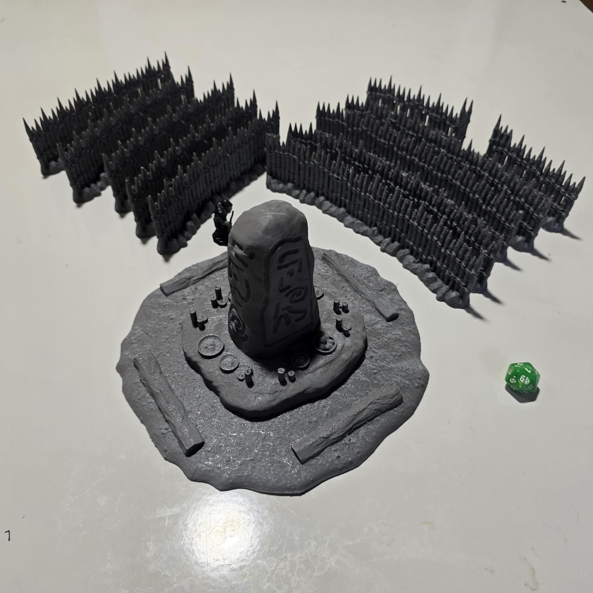 Unpainted gray PLA captures the rough ground, carved runestone, and jagged timber spikes of this 28 mm tabletop terrain set. The monolith rises from a layered base scattered with simple offerings, while the spiked walls form a full circle around the site. Each piece shows the subtle lines of 3D printed construction, ready for primer. Designed for DnD / Pathfinder / wargaming on a 1-inch grid, it stands as a stark landmark on any table.