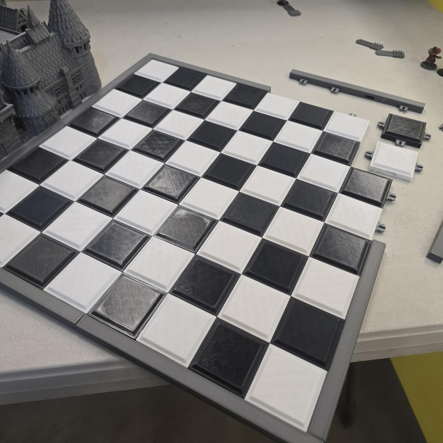 Close-up of interlocking snap-fit chess board tiles showing raised square construction system