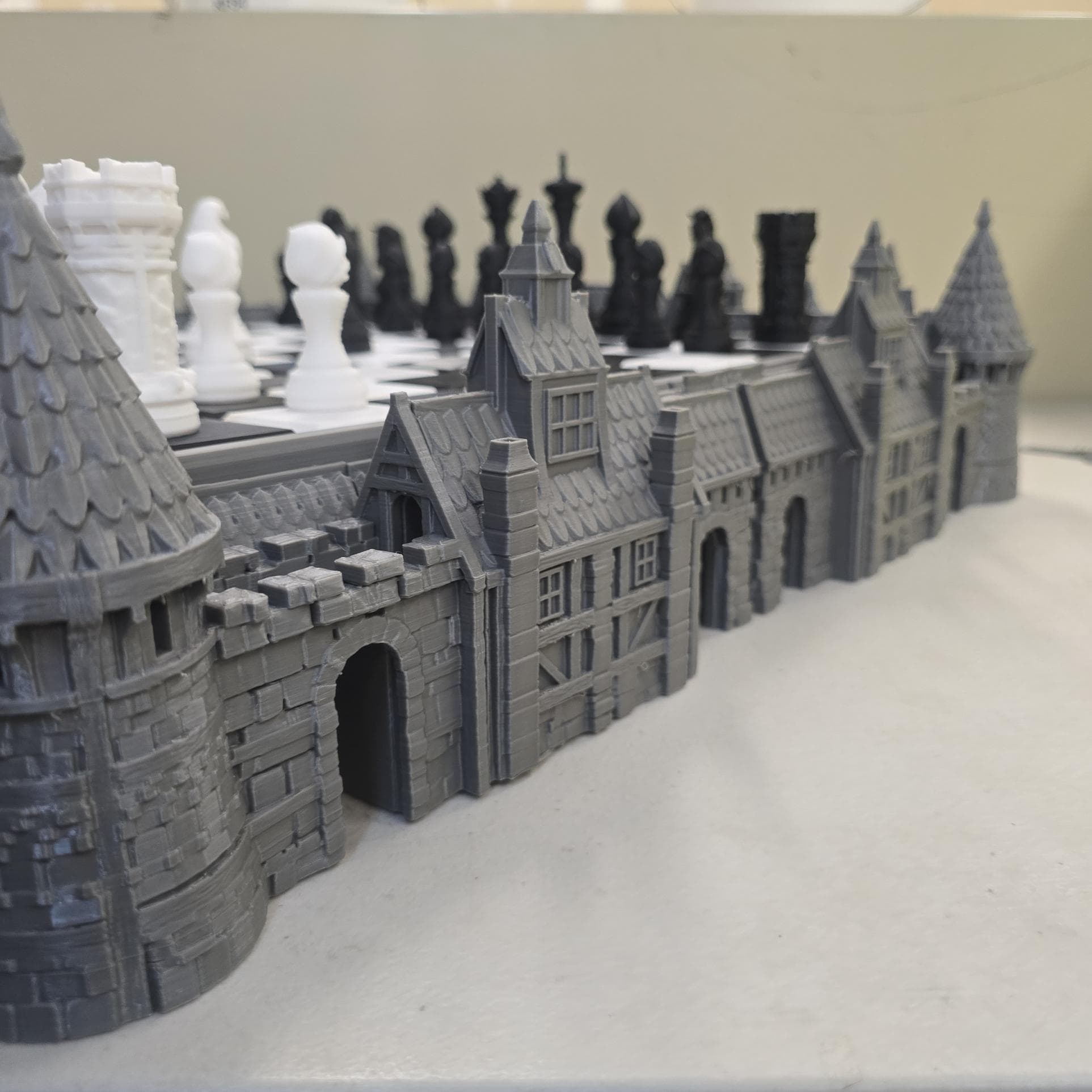 3D printed castle base surrounding raised chess board with towers, rooftops and stone wall detailing