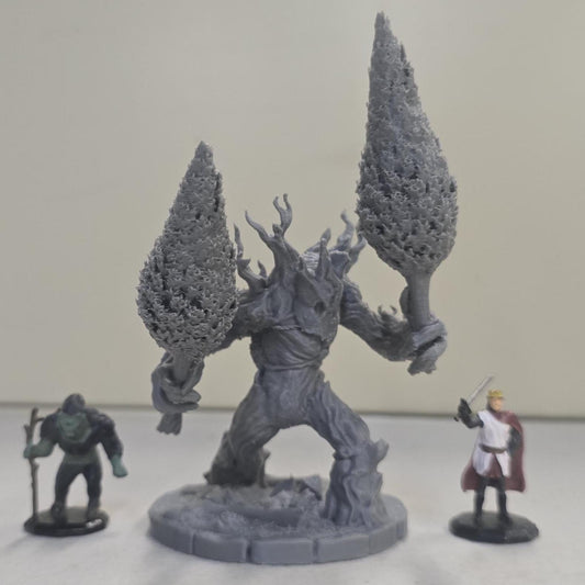 This large-scale Mossfang the Rootbreaker forest ent miniature is 3D printed in gray PLA and scaled for 28mm tabletop gaming. Standing nearly three times taller than standard humanoid miniatures, Mossfang grips two uprooted trees as weapons and features detailed bark textures, root-covered base detailing, and a wide stance for dramatic tabletop presence.