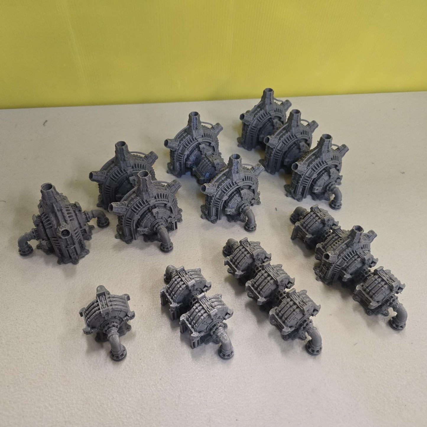 Grimdark power generator cells with ribbed housings, arched industrial frames, vent stacks, and curved pipe connections. Scaled for DnD / Pathfinder / wargaming. Miniatures and a D20 to show their footprint on a 1-inch grid. Several variants appear as single units and linked multi-cell arrays, giving the set the look of a dense industrial power system. Built as sci-fi scatter terrain, these generator cells bring heavy mechanical detail and battlefield atmosphere to any tabletop terrain layout.