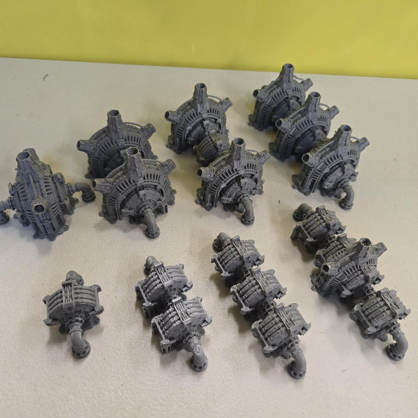 Grimdark power generator cells with ribbed housings, arched industrial frames, vent stacks, and curved pipe connections. Scaled for DnD / Pathfinder / wargaming. Miniatures and a D20 to show their footprint on a 1-inch grid. Several variants appear as single units and linked multi-cell arrays, giving the set the look of a dense industrial power system. Built as sci-fi scatter terrain, these generator cells bring heavy mechanical detail and battlefield atmosphere to any tabletop terrain layout.