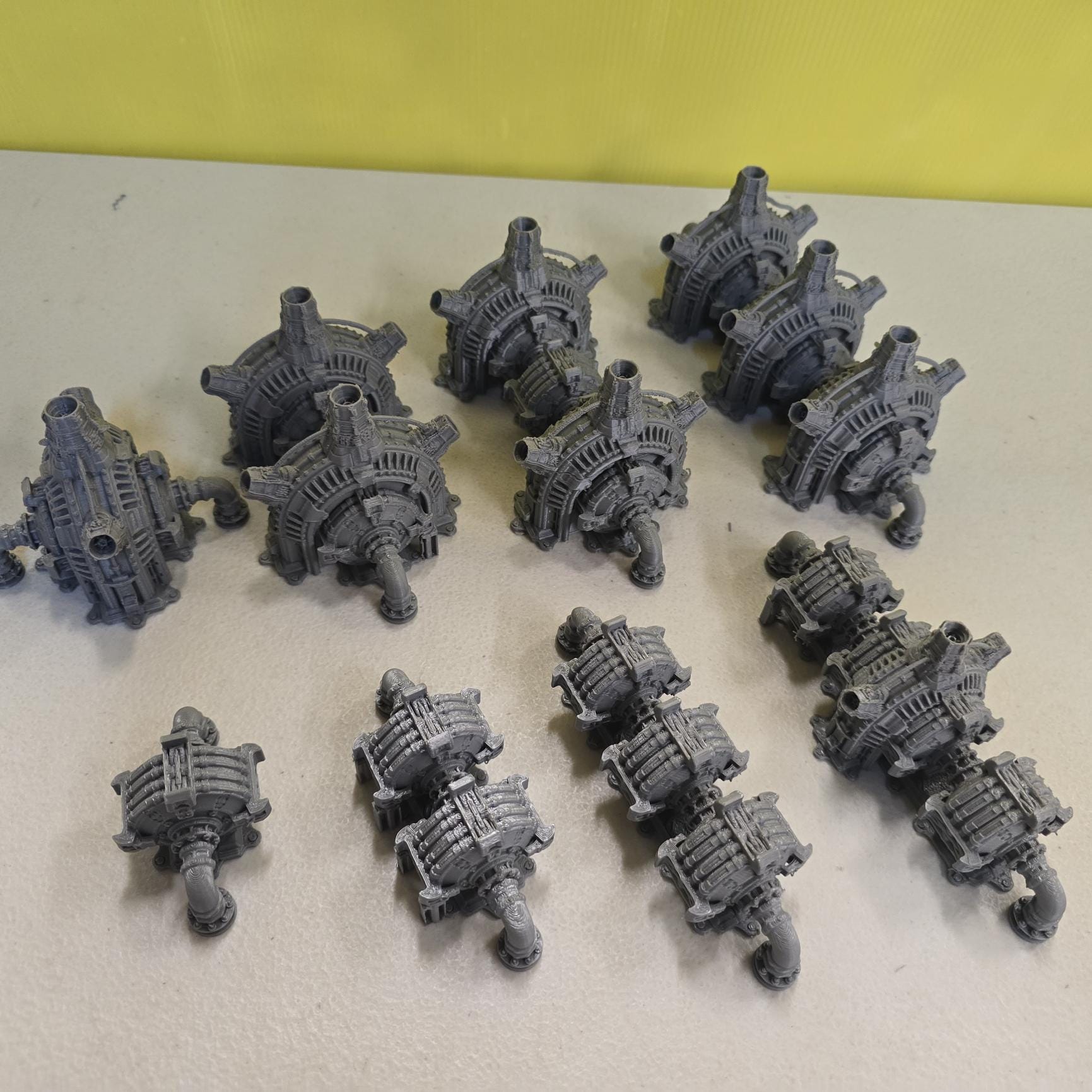 Grimdark power generator cells with ribbed housings, arched industrial frames, vent stacks, and curved pipe connections. Scaled for DnD / Pathfinder / wargaming. Miniatures and a D20 to show their footprint on a 1-inch grid. Several variants appear as single units and linked multi-cell arrays, giving the set the look of a dense industrial power system. Built as sci-fi scatter terrain, these generator cells bring heavy mechanical detail and battlefield atmosphere to any tabletop terrain layout.