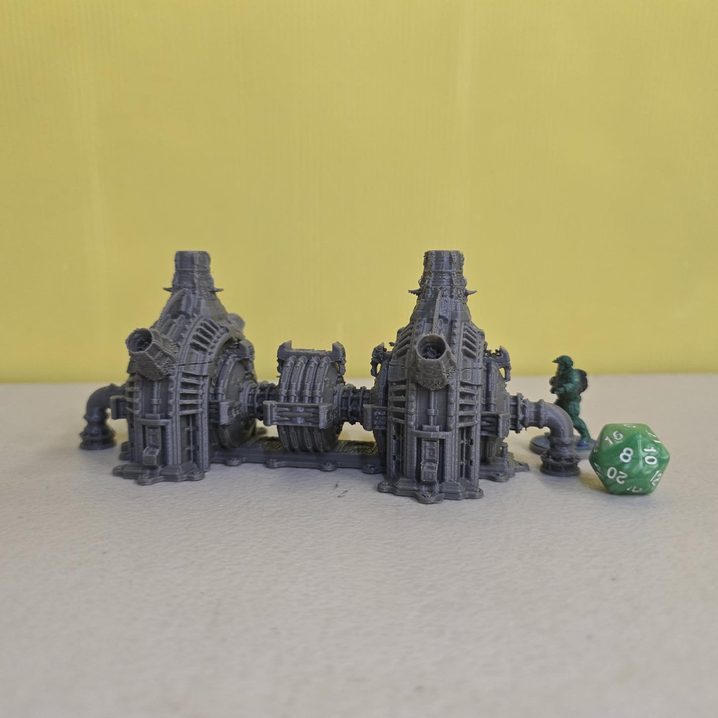 Grimdark power generator cells with ribbed housings, arched industrial frames, vent stacks, and curved pipe connections. Scaled for DnD / Pathfinder / wargaming. Miniatures and a D20 to show their footprint on a 1-inch grid. Several variants appear as single units and linked multi-cell arrays, giving the set the look of a dense industrial power system. Built as sci-fi scatter terrain, these generator cells bring heavy mechanical detail and battlefield atmosphere to any tabletop terrain layout.